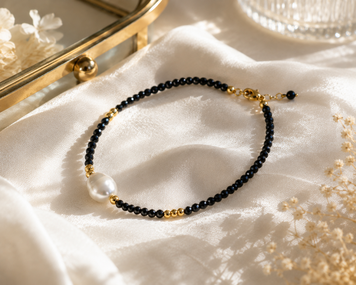 Black bead bracelet with a white freshwater pearl, gold-tone lobster clasp and short extension chain