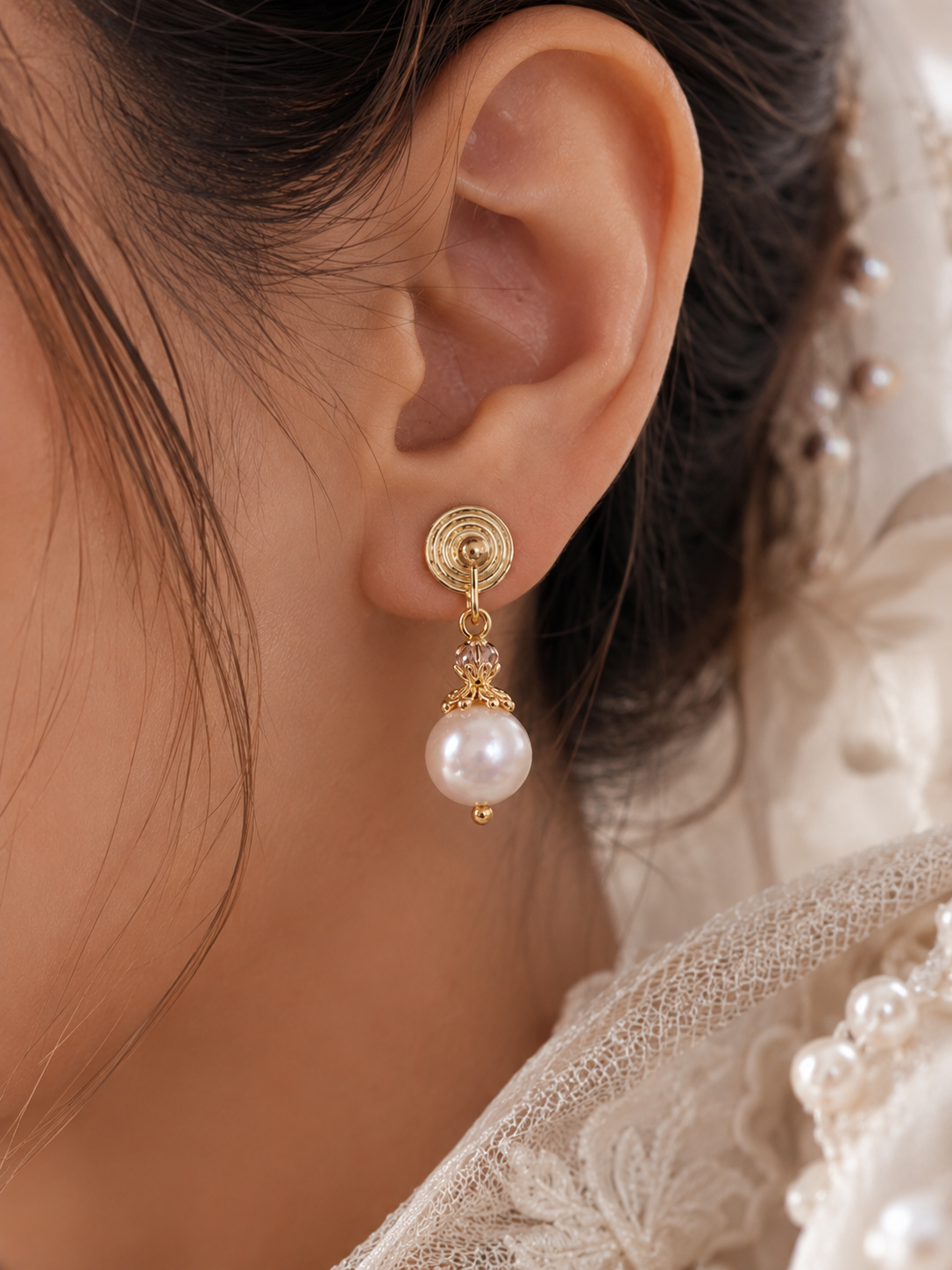 Close-up of a gold spiral drop earring with a white freshwater pearl