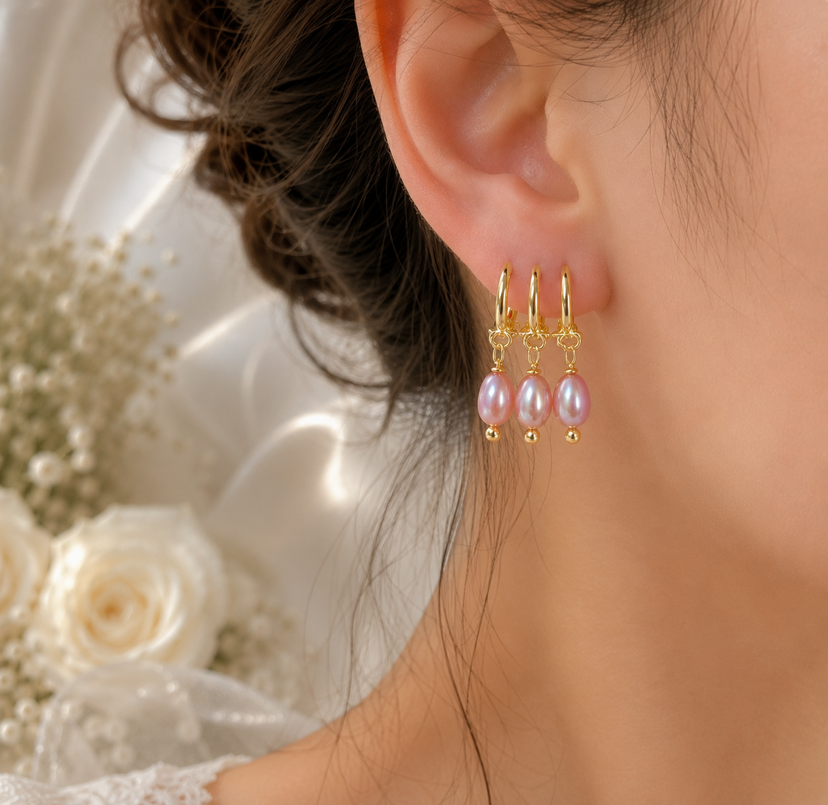 Close-up of one pink freshwater pearl earring featuring three gold-tone hoops and three pearl drops