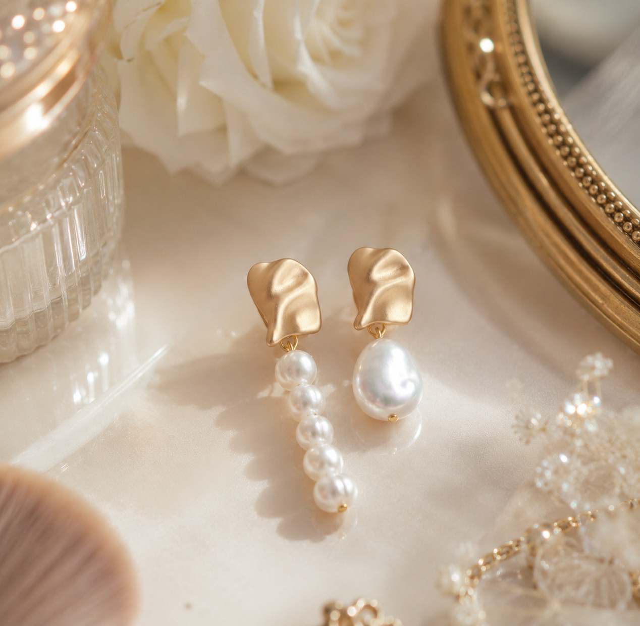 Mismatched freshwater pearl earrings arranged beside bridal accessories