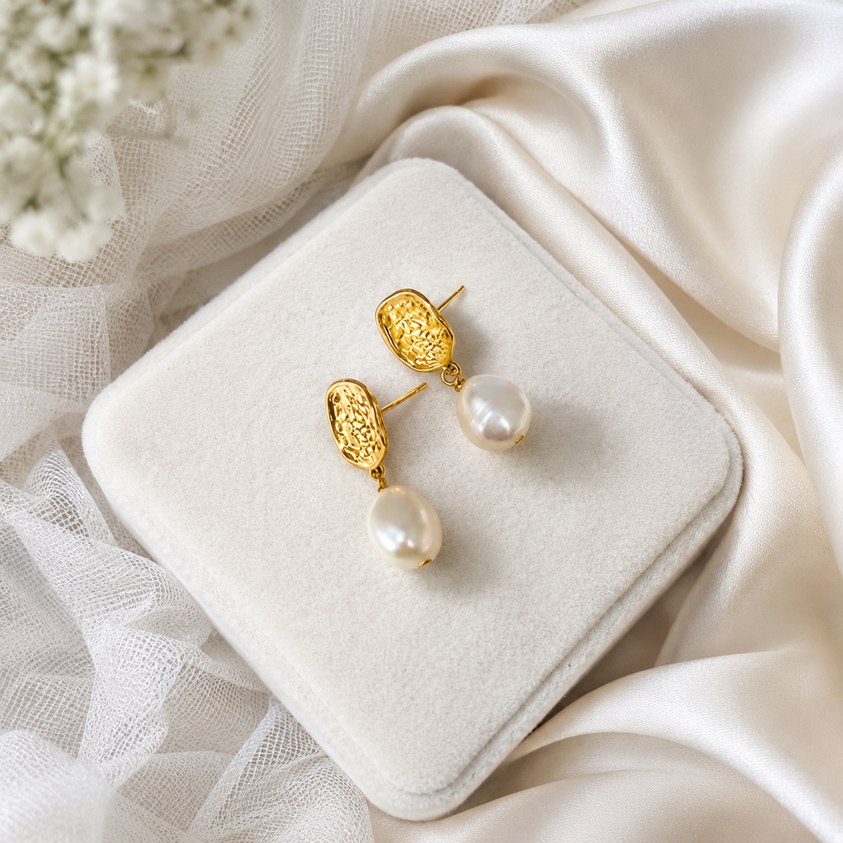 White baroque pearl and textured gold-tone drop earrings showing post closures