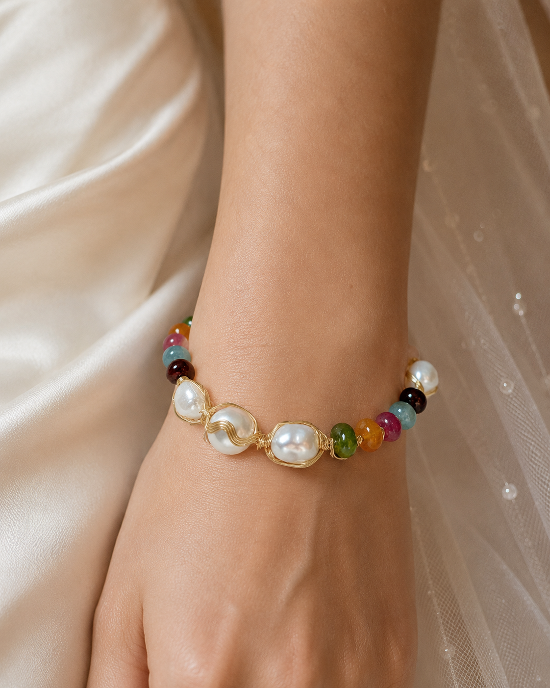 White baroque freshwater pearl bracelet with multicolor beads and gold-tone wire details worn on the wrist