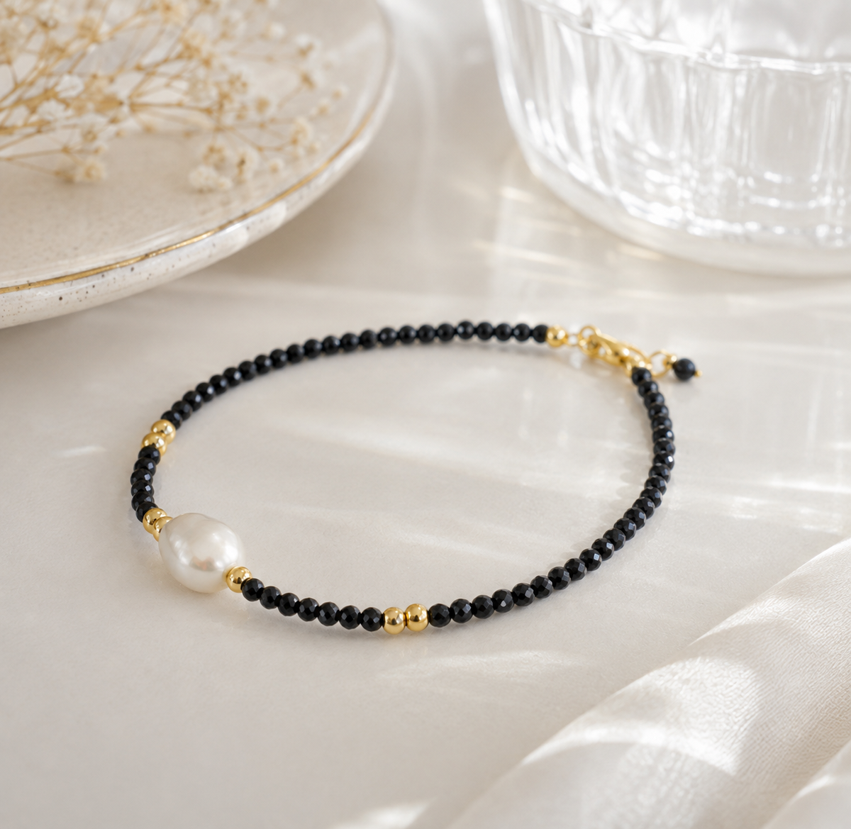 Black faceted bead bracelet featuring a single white freshwater pearl and gold-tone spacer beads
