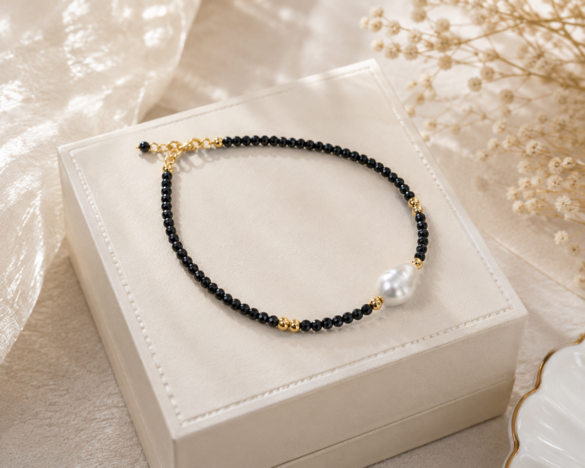 Black faceted bead and freshwater pearl bracelet displayed on a white jewelry box