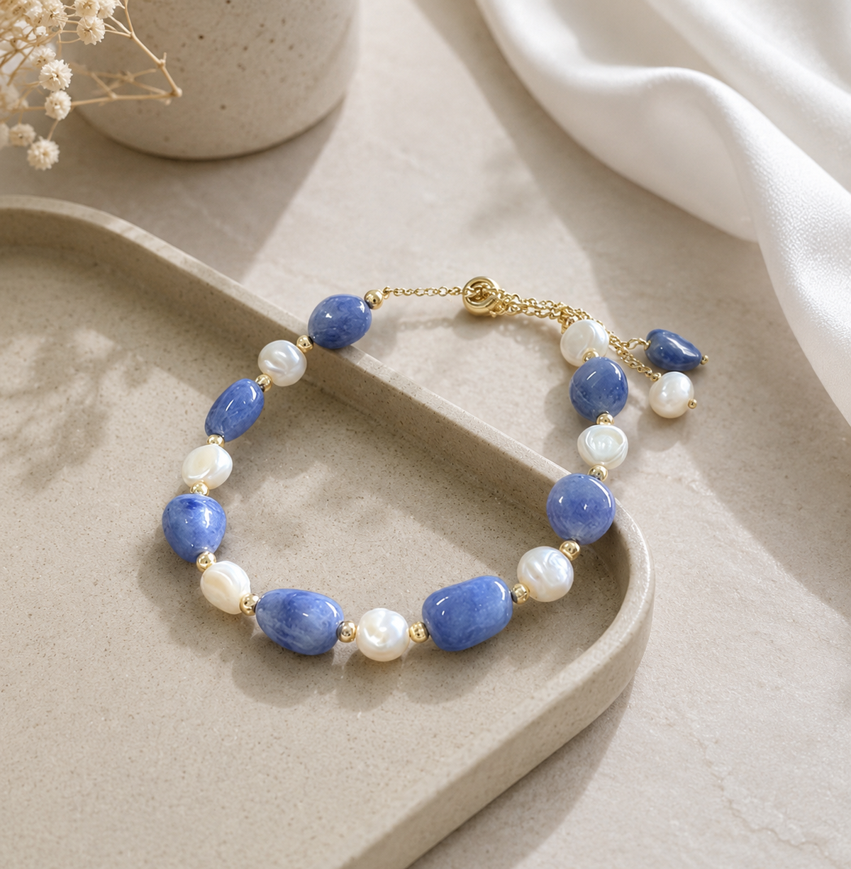 Blue stone bracelet with white pearl accents and a gold-tone extension chain