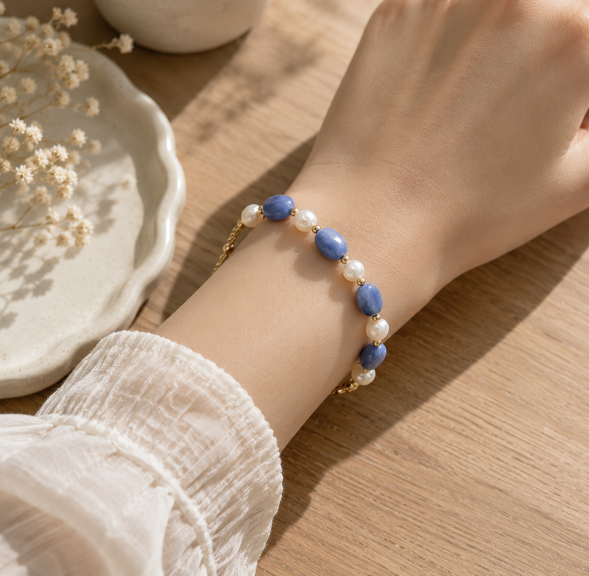 Close-up of a blue stone and white pearl beaded bracelet worn on the wrist