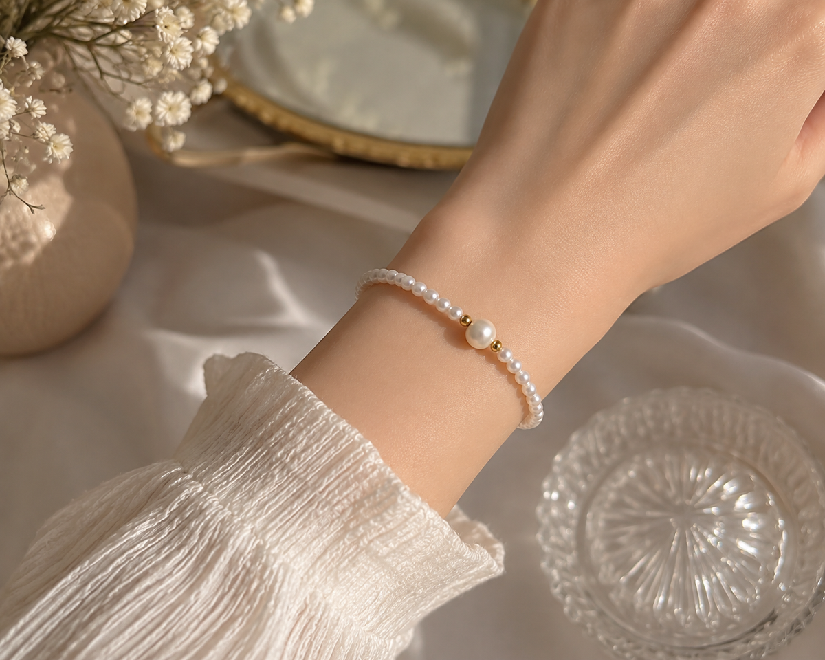 Dainty white pearl stretch bracelet with a larger centerpiece pearl and gold-tone accents