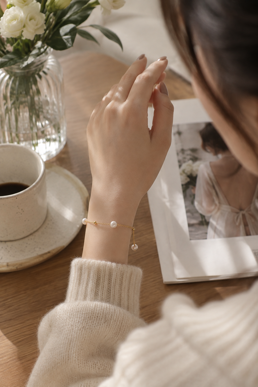 Delicate white pearl bracelet with gold-tone bead accents worn on the wrist