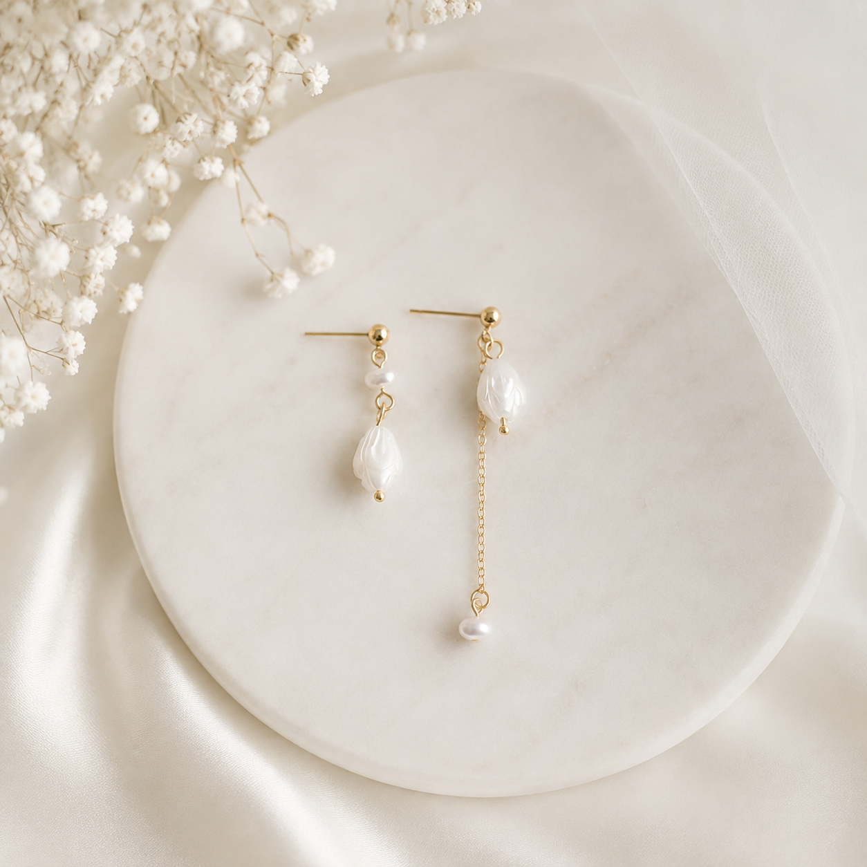 Asymmetric freshwater pearl floral drop earrings displayed with bridal veil and flowers