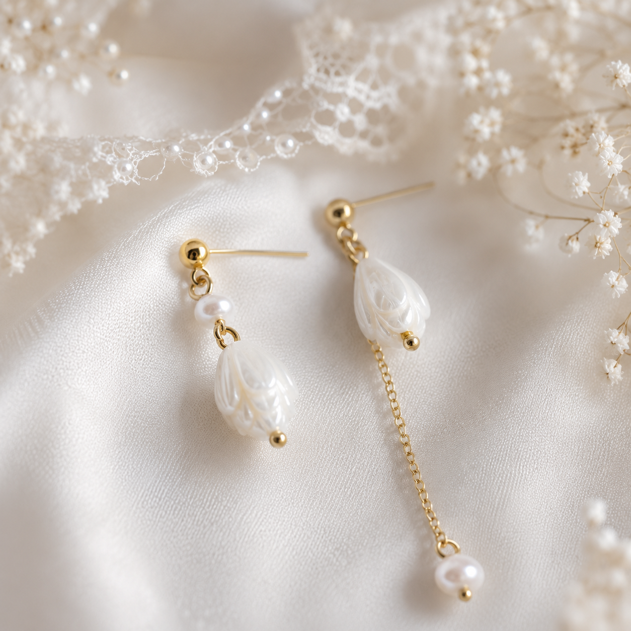 Close-up of asymmetric pearl floral earrings arranged on ivory satin