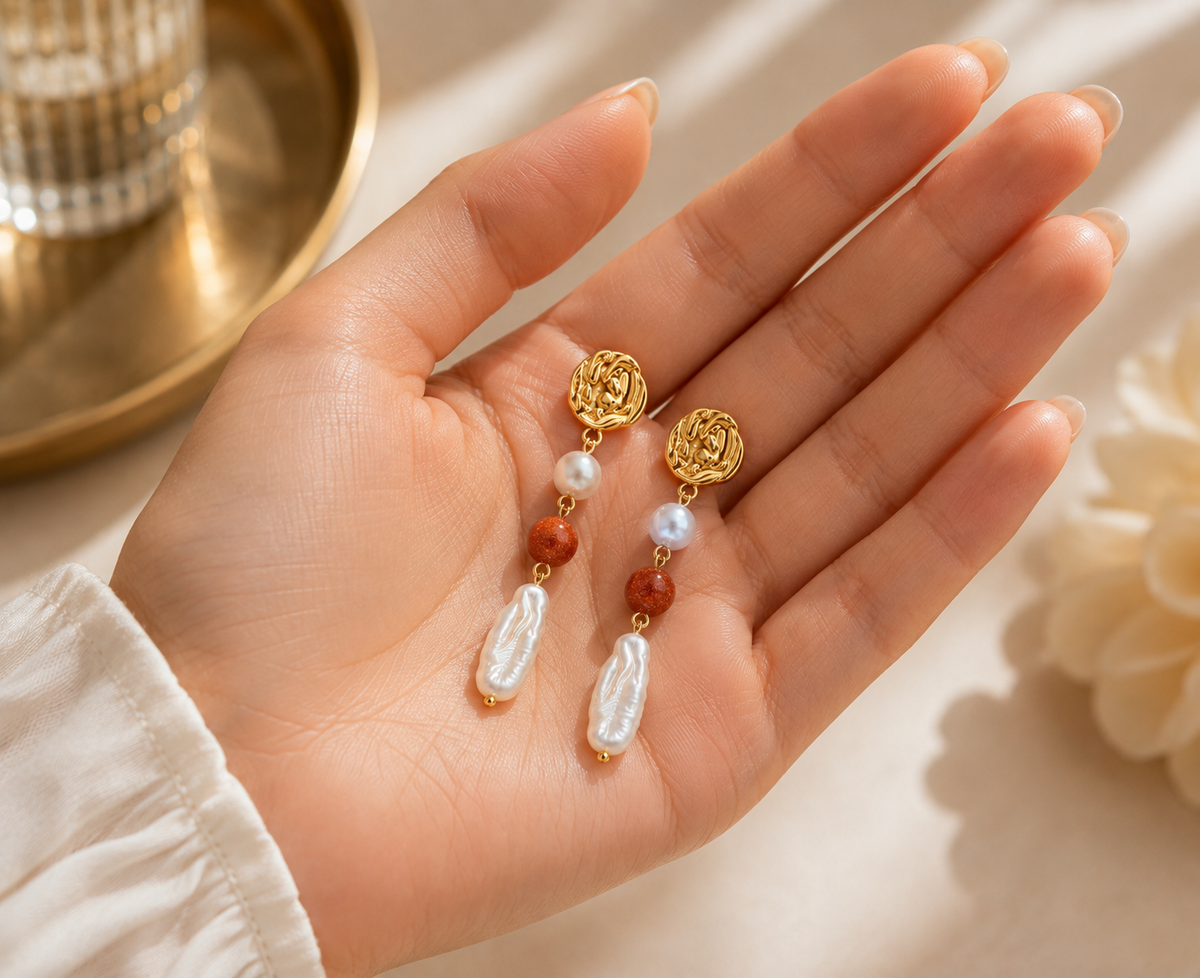 Pair of freshwater pearl beaded drop earrings displayed in a hand