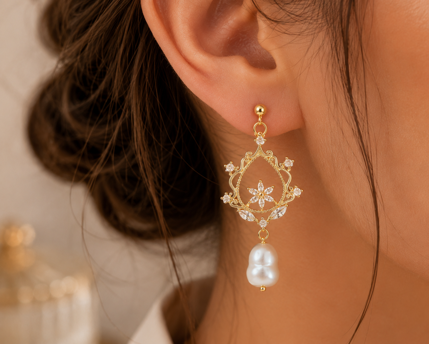 Close-up of a freshwater pearl drop earring with floral filigree and sparkling accents
