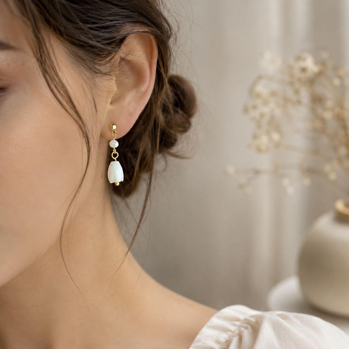 Close-up of the shorter freshwater pearl floral drop earring worn on the ear