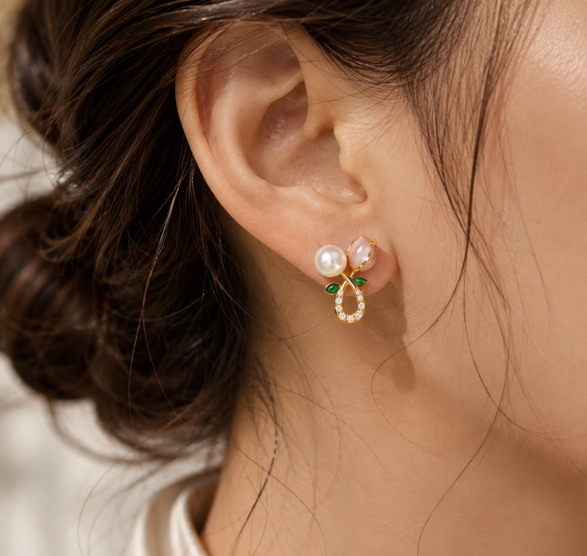 Close-up of a freshwater pearl floral stud earring with pink and green details