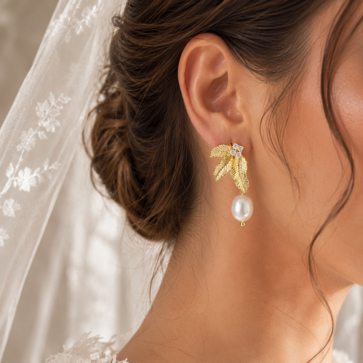 Side view of a gold leaf earring with a dangling white freshwater pearl
