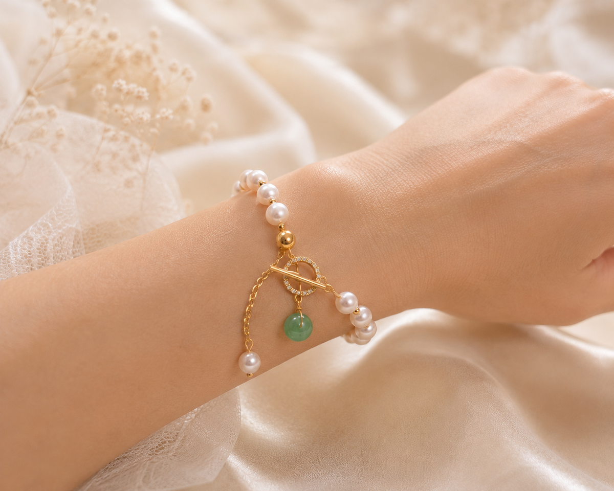 Bride wearing a white freshwater pearl bracelet with green bead and gold-tone details