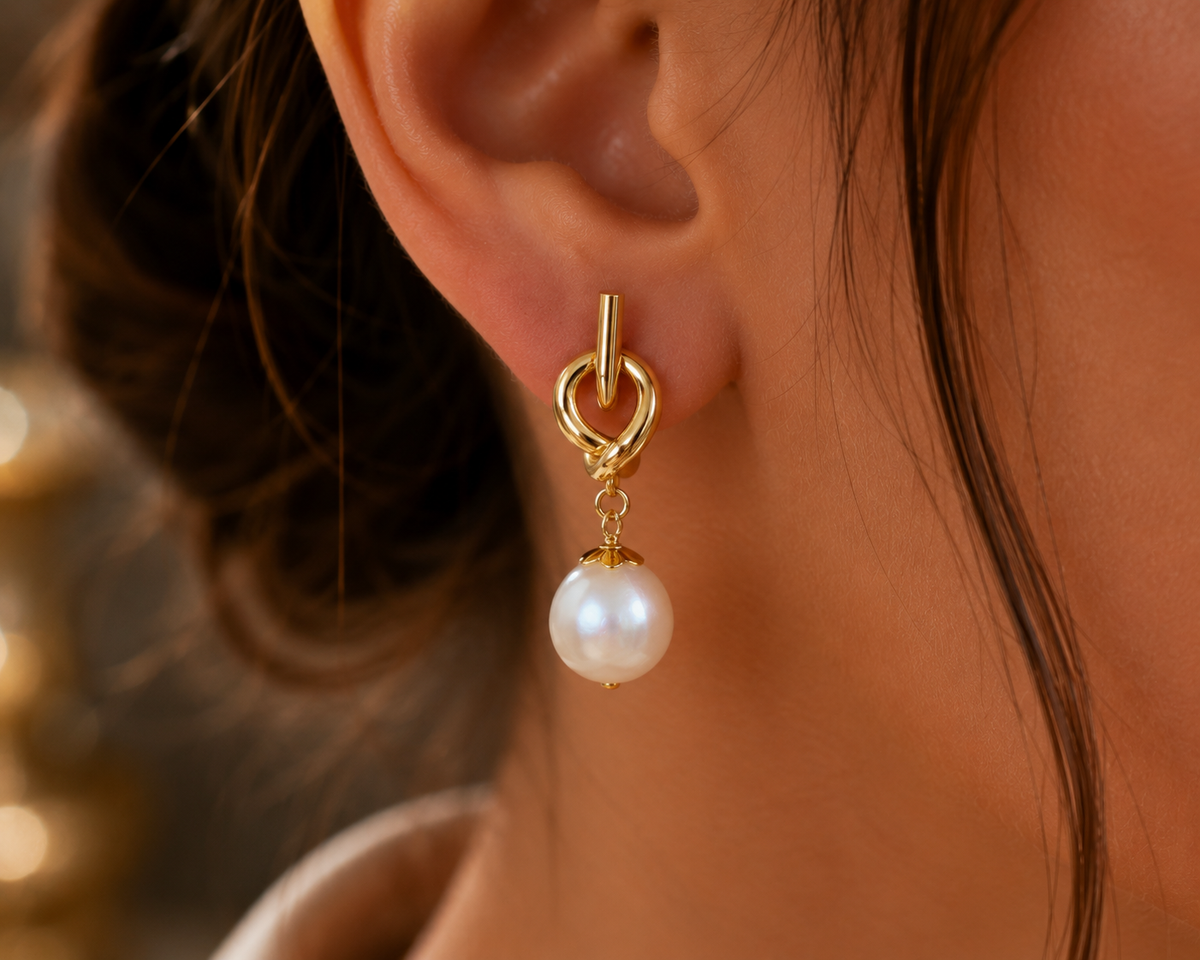 Close-up of a freshwater pearl drop earring with a gold-tone knot stud