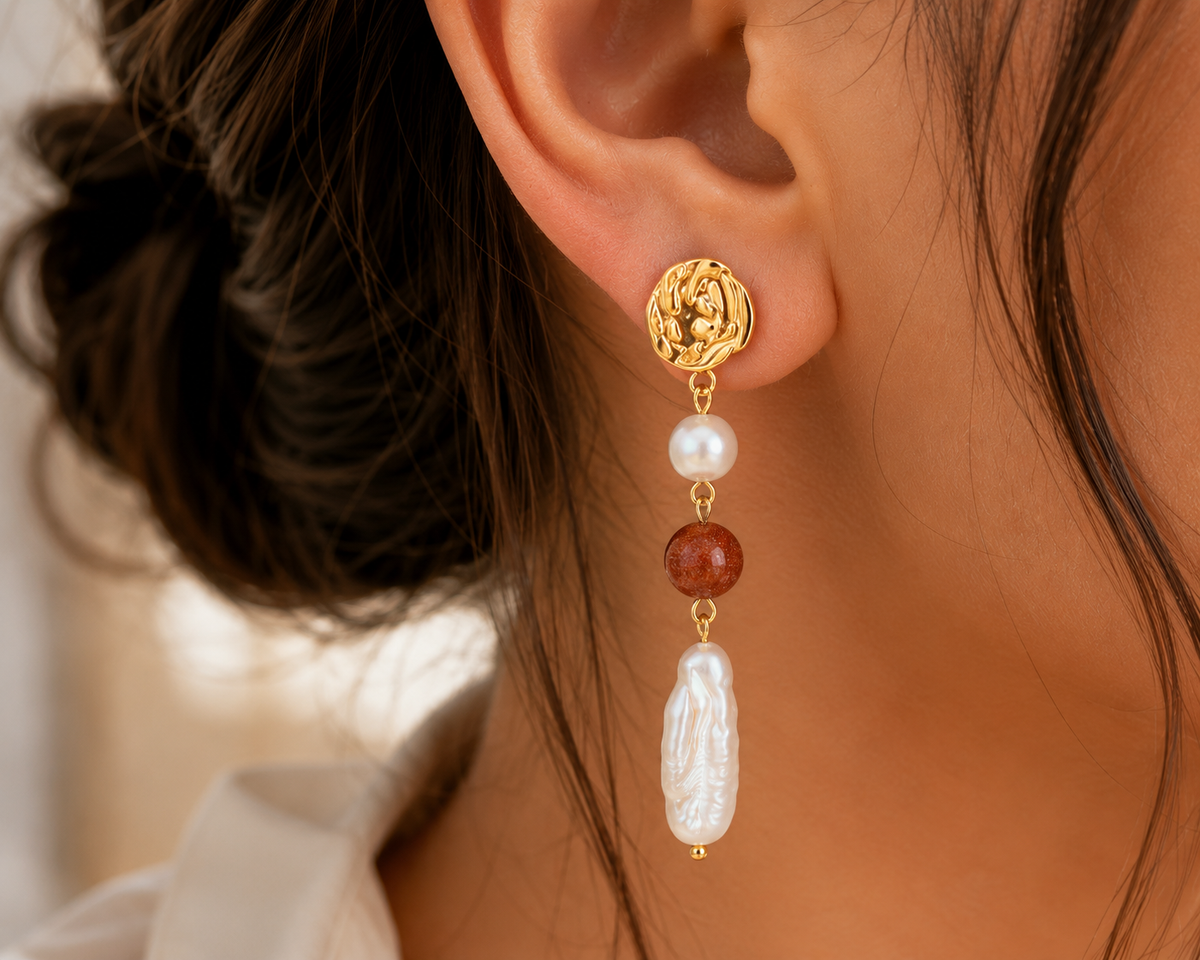 Close-up of a freshwater pearl long drop earring with a warm-toned bead