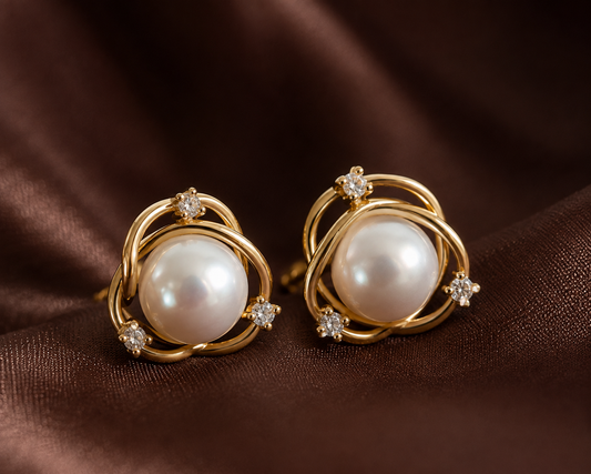 Close-up of freshwater pearl orbit stud earrings on brown satin