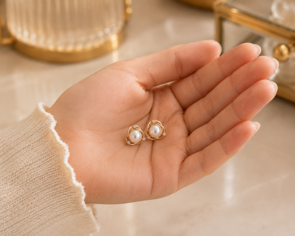 Pair of freshwater pearl orbit stud earrings displayed in a hand