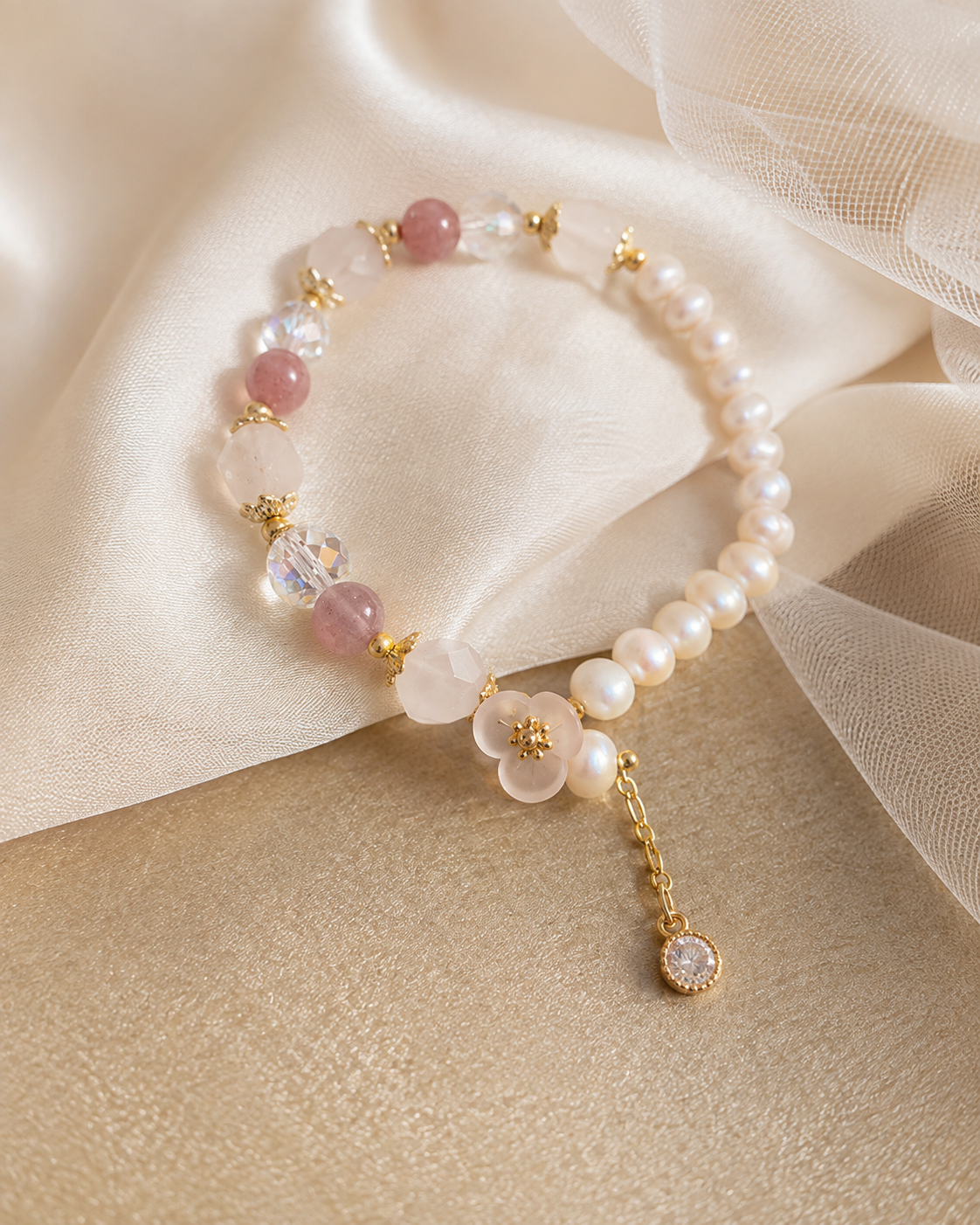 Freshwater pearl bracelet with pink beads, a flower charm and gold-tone details displayed on satin