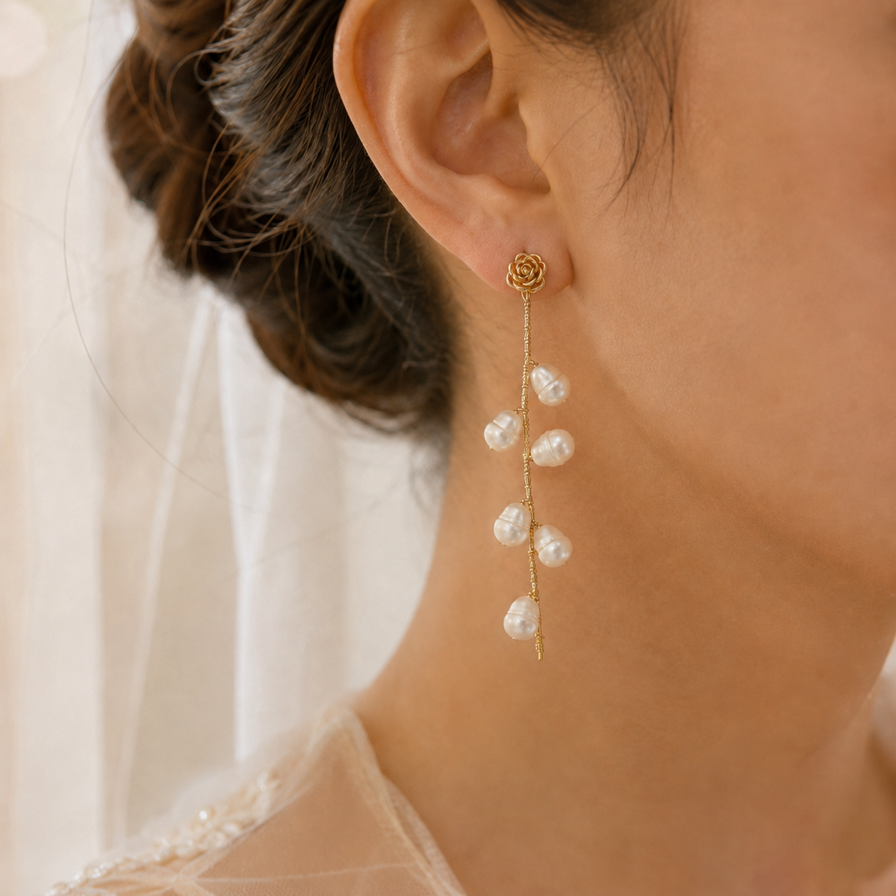 Close-up of a freshwater pearl rose vine drop earring worn on the ear