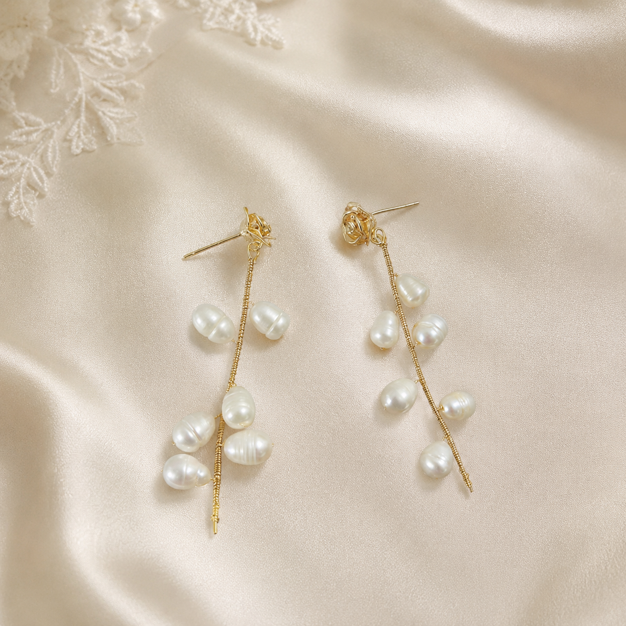 Pair of gold-tone rose vine earrings with cascading freshwater pearls on satin