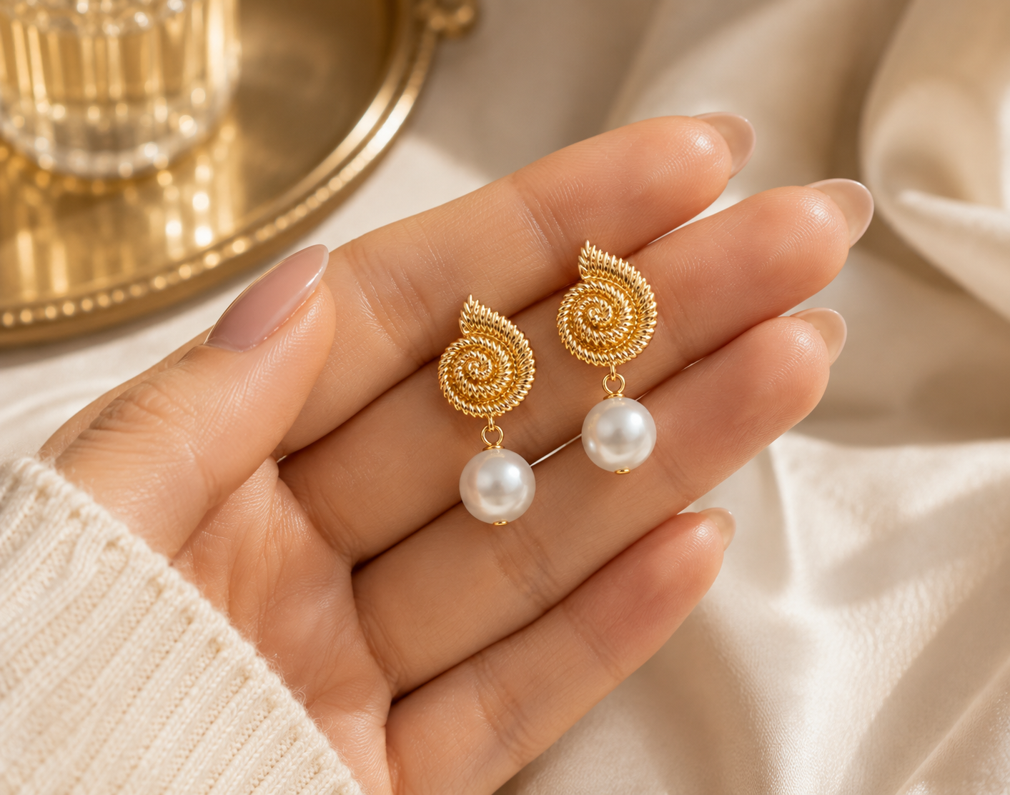 Pair of freshwater pearl spiral drop earrings displayed in a hand