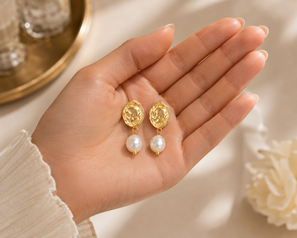 Pair of freshwater pearl vintage coin drop earrings displayed in a hand