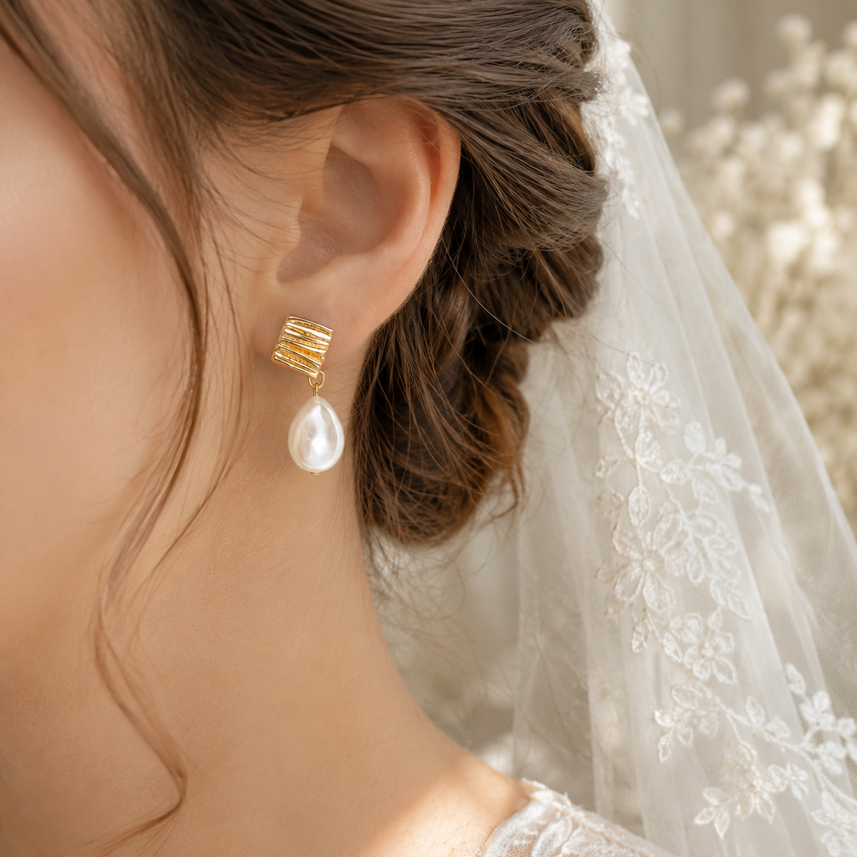 Bride wearing geometric gold stud earrings with luminous teardrop pearls