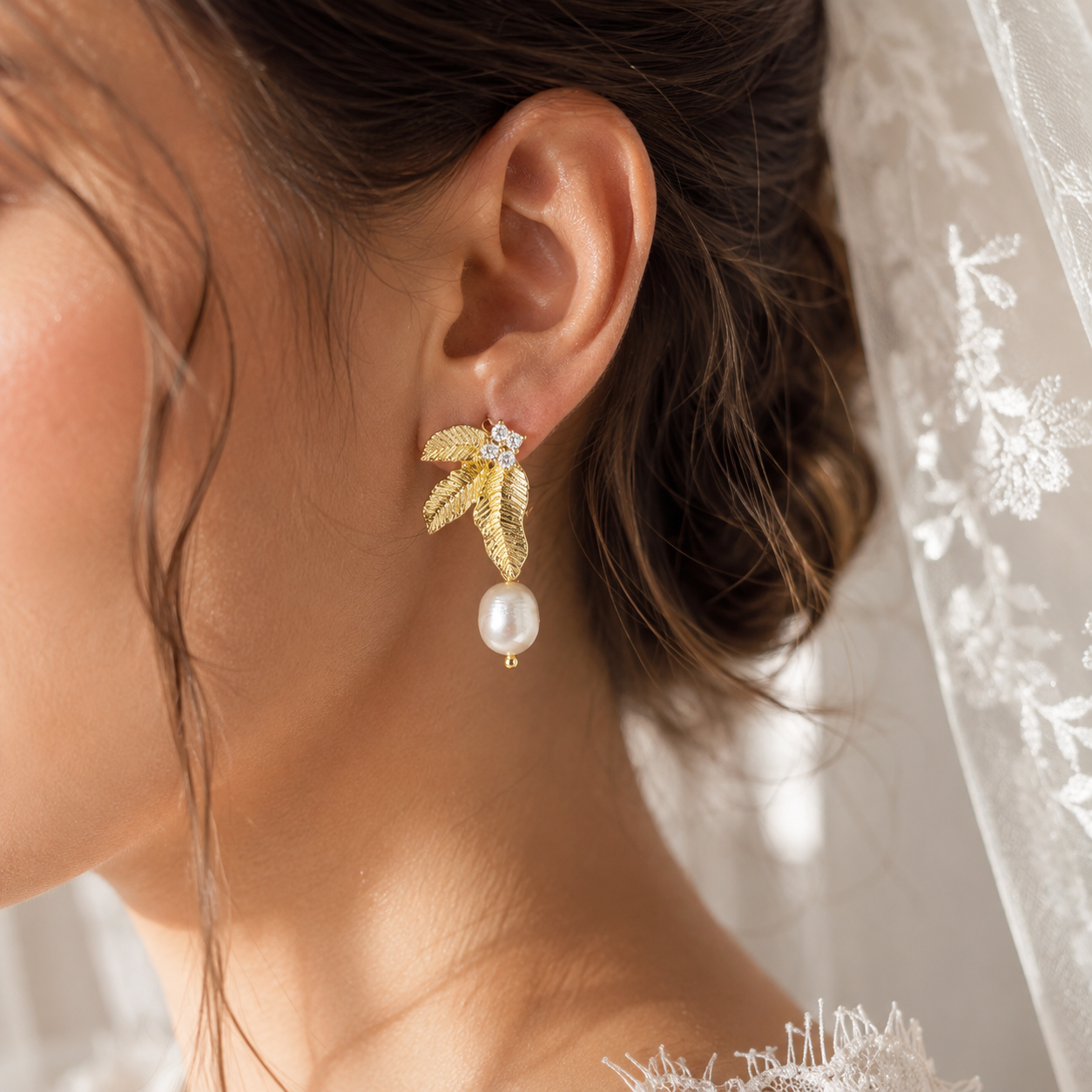 Bride wearing gold leaf dangle earrings with white freshwater pearls