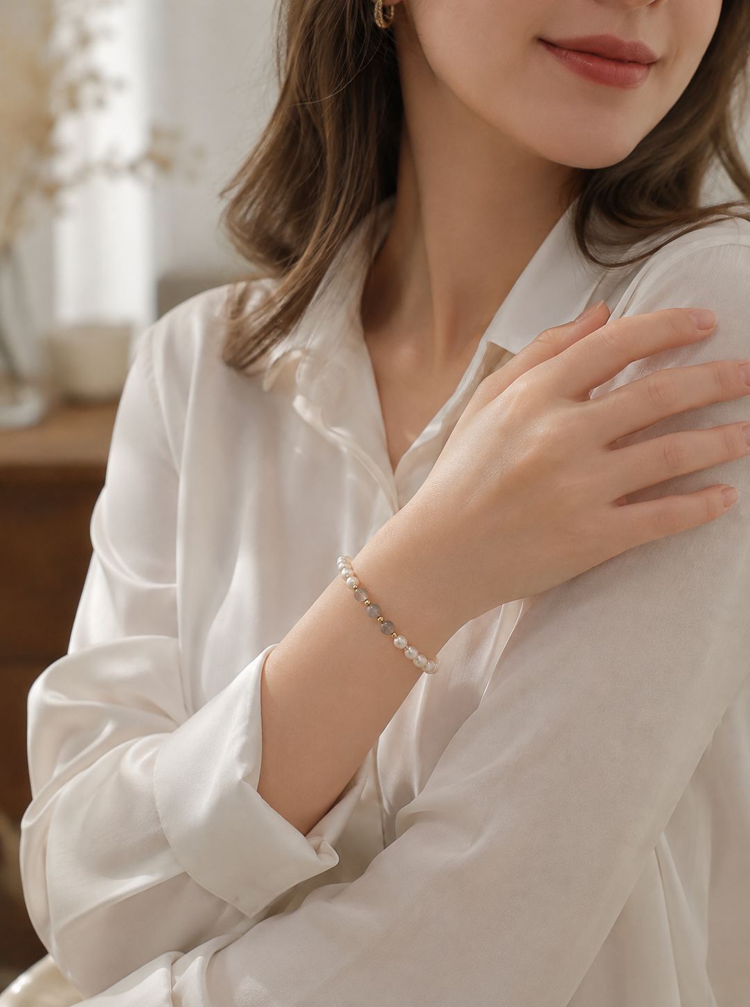 Woman wearing a gray bead and white pearl stretch bracelet with a white blouse