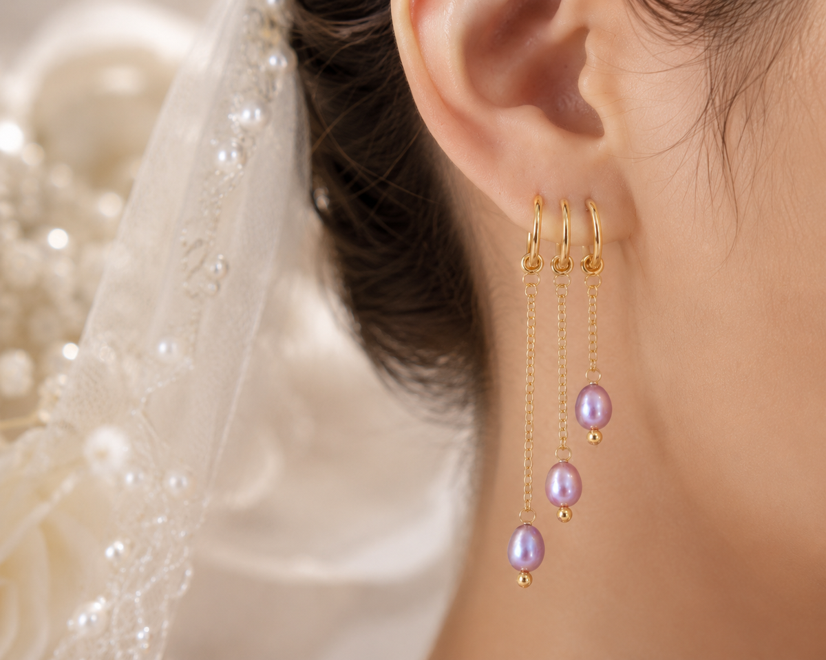Close-up of a gold-tone triple chain earring with lavender freshwater pearl drops