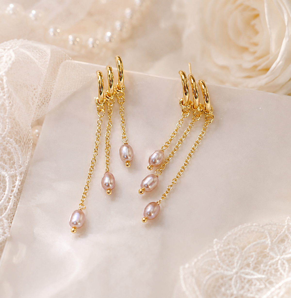 Pair of lavender freshwater pearl triple chain earrings displayed on bridal fabric