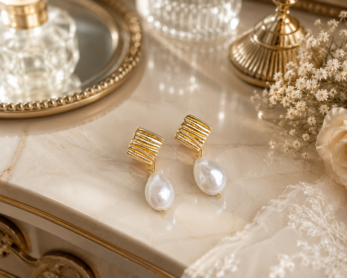 Linear gold stud and white pearl earrings displayed on a bridal vanity
