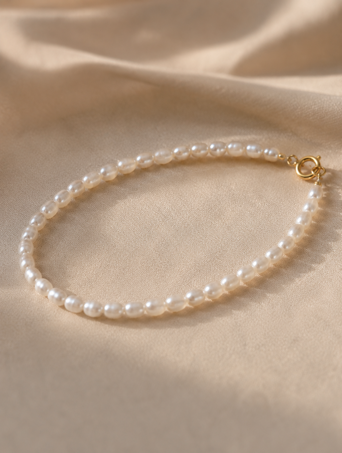 Minimalist bracelet featuring a delicate strand of small white freshwater pearls and gold tone hardware