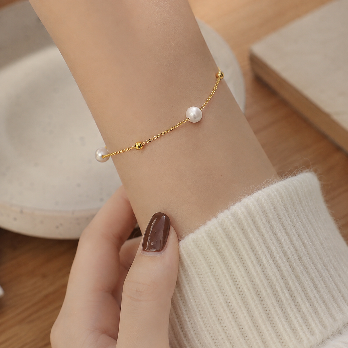 Minimalist white pearl and gold-tone slider bracelet worn on a woman’s wrist