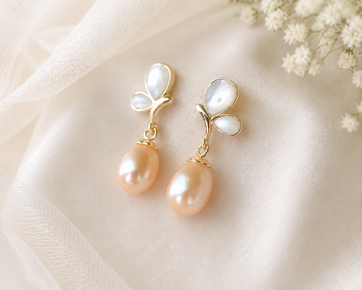 Pair of peach freshwater pearl dangle earrings with white butterfly-shaped studs