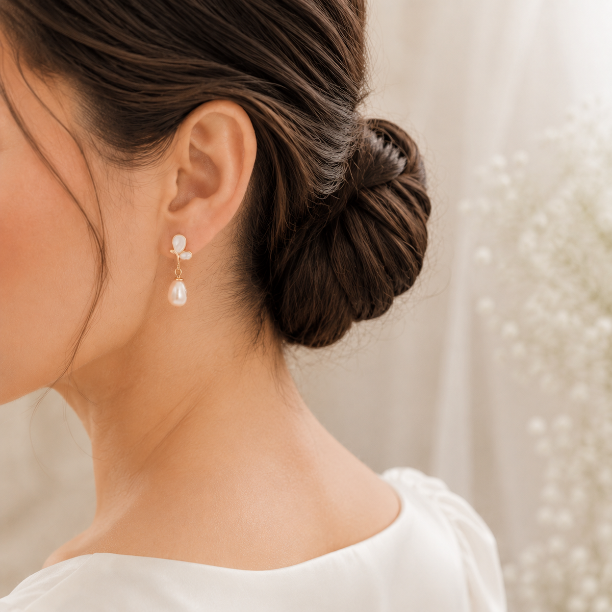 Bride wearing gold-tone butterfly earrings with dangling peach freshwater pearls