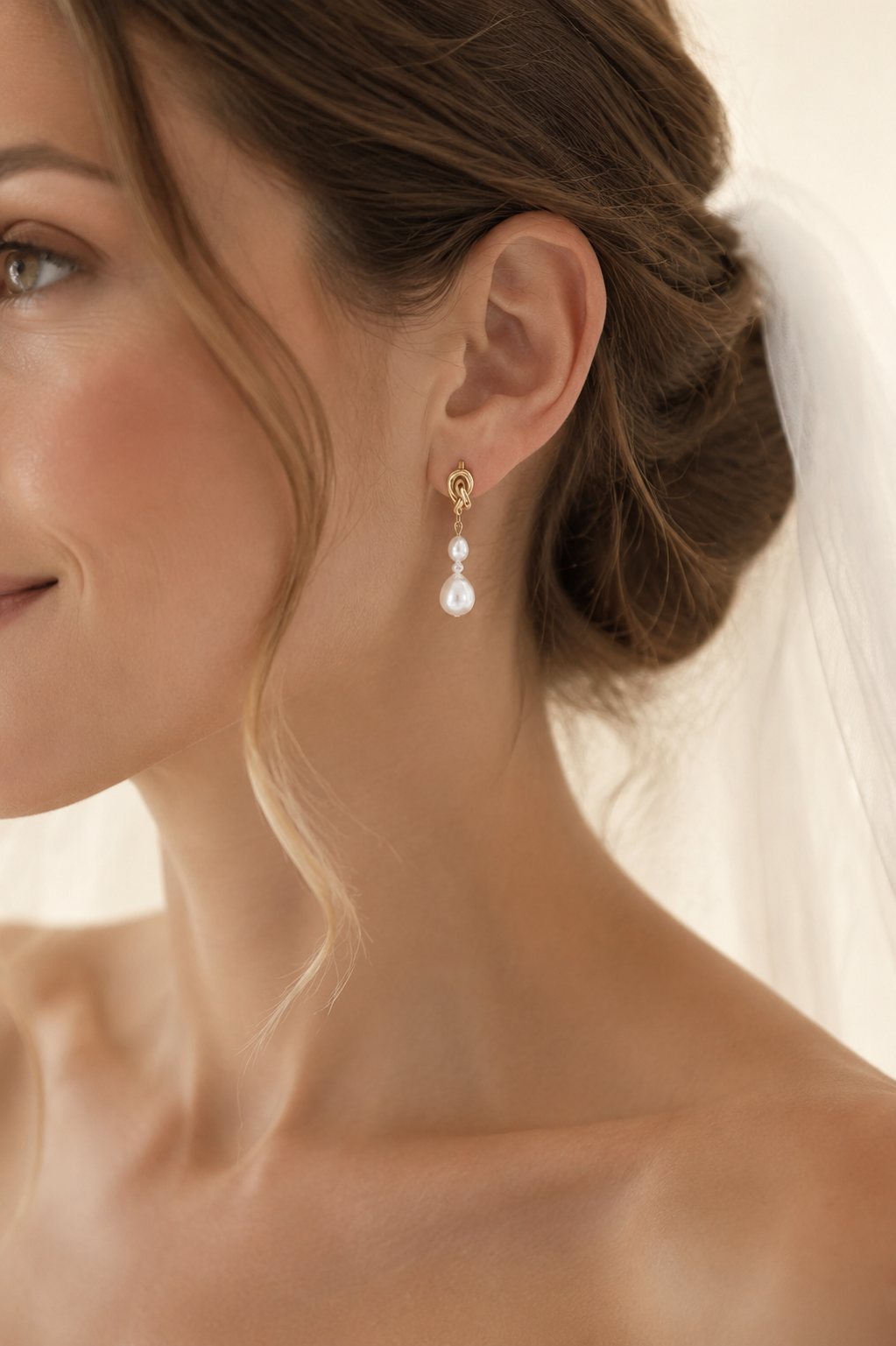 Bride wearing graduated white freshwater pearl earrings with gold knot studs
