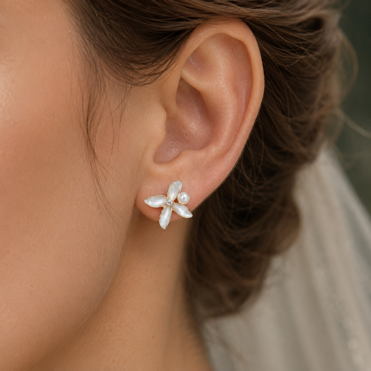 Close-up of a pearlescent flower stud earring with a round freshwater pearl