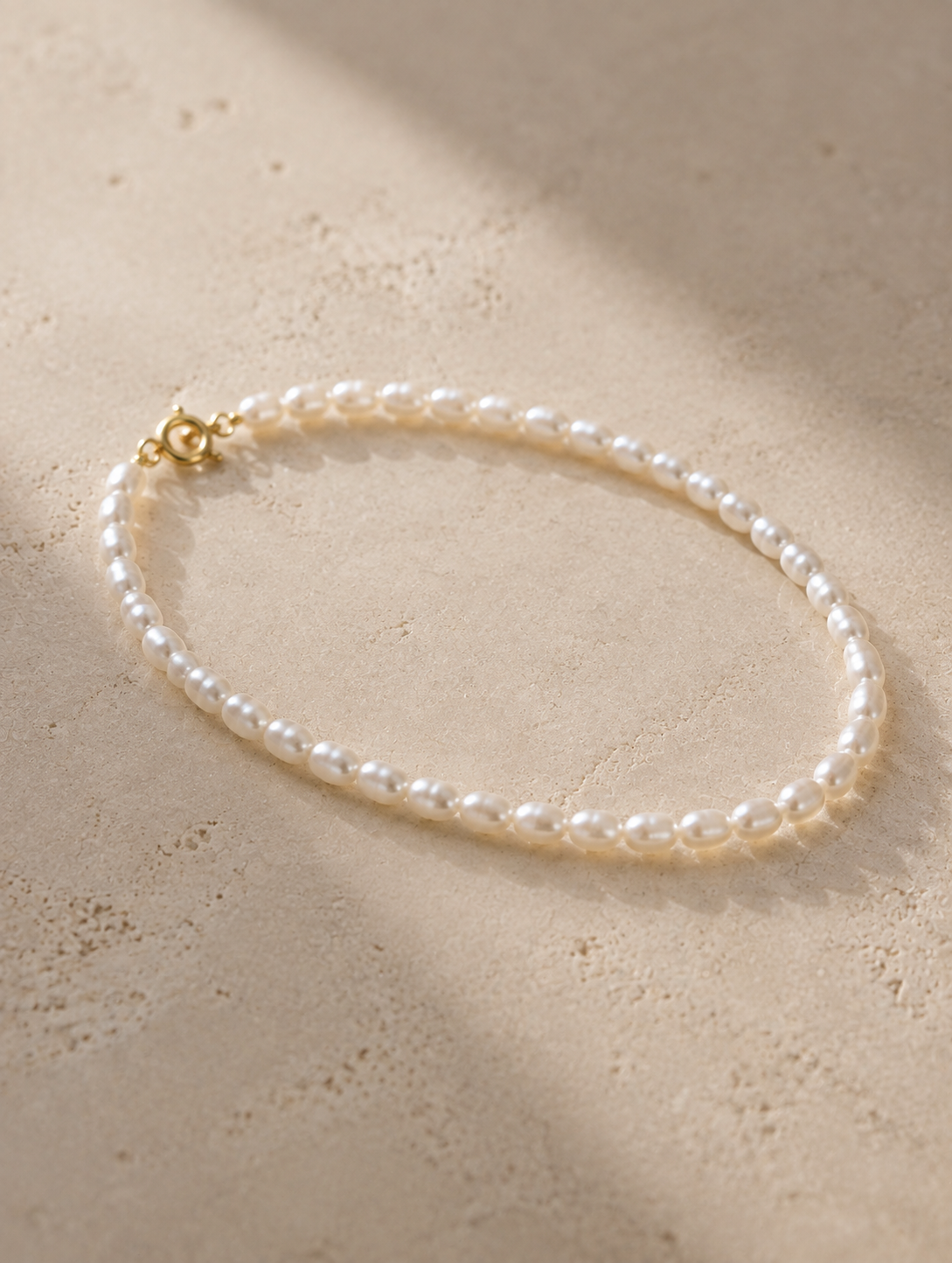Full view of a slender bracelet made with petite oval freshwater pearls