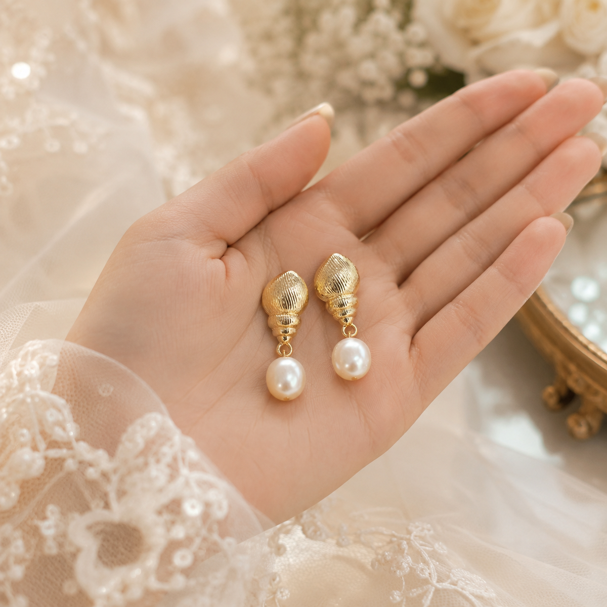 Pair of sculpted shell and freshwater pearl earrings displayed in hand for size reference