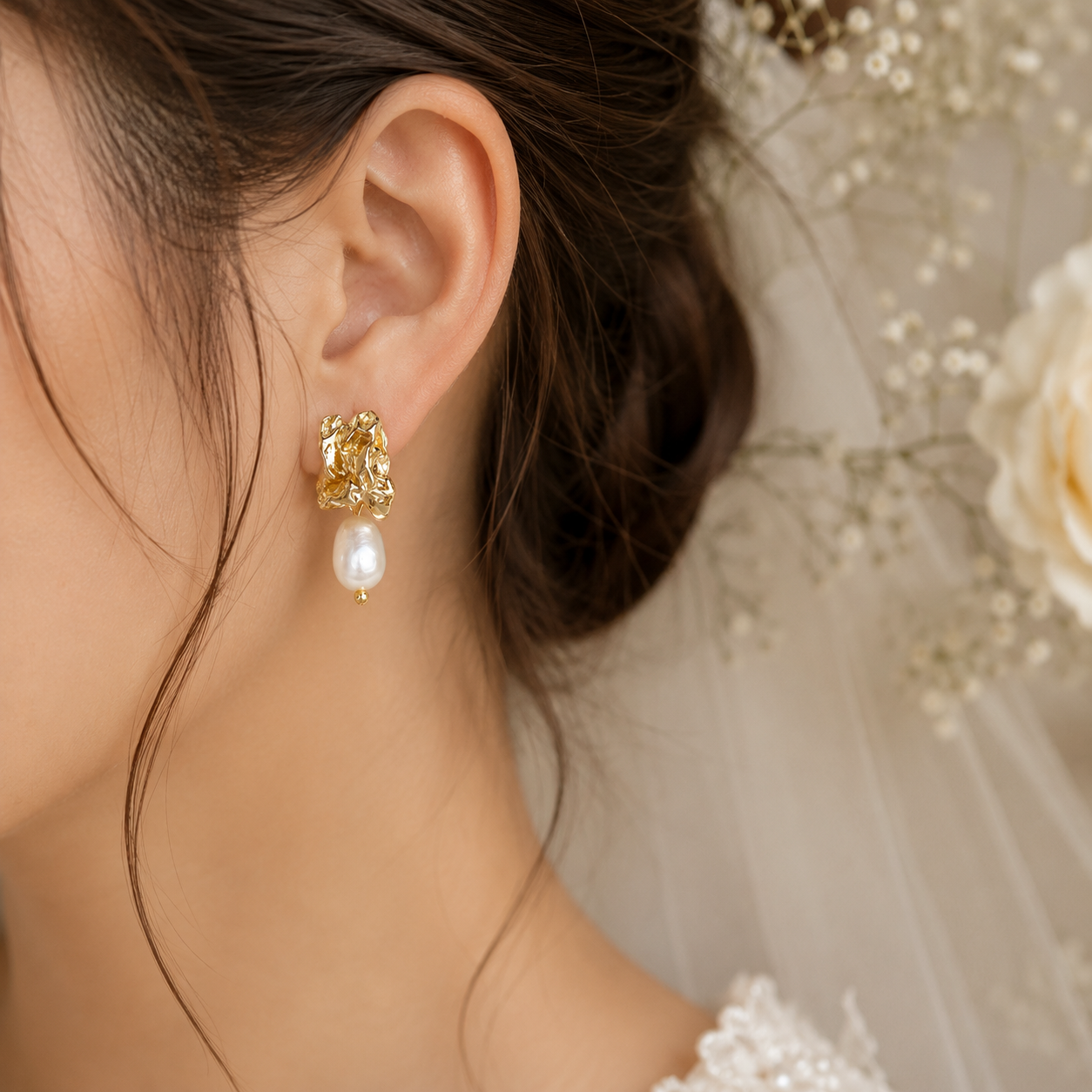 Bride wearing sculptural gold-tone earrings with white baroque pearl drops