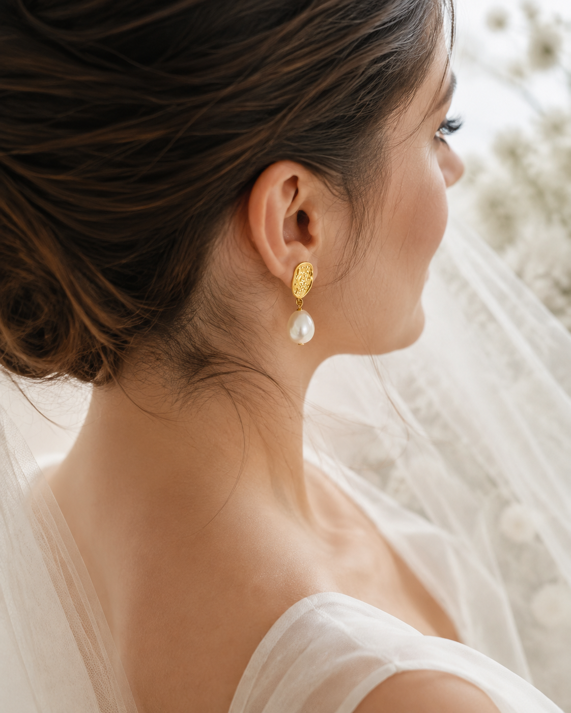 Bride wearing textured gold-tone earrings with dangling white baroque pearls