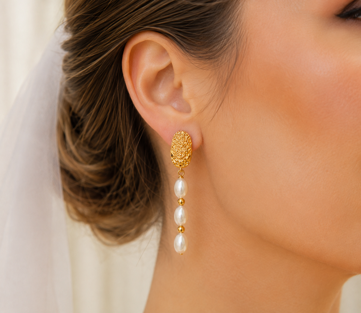 Right-side view of textured oval gold earrings with three freshwater pearls