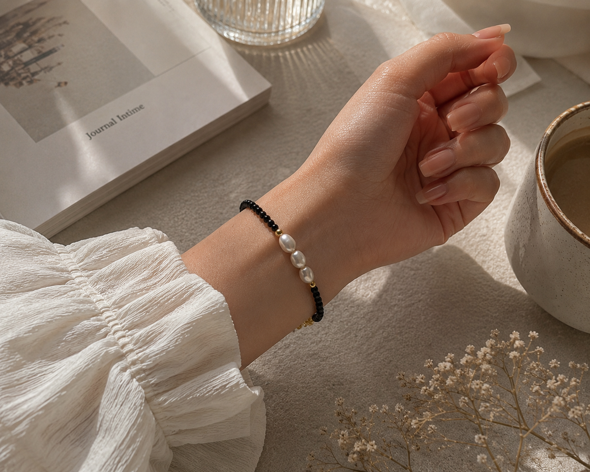 Close-up of a black beaded bracelet featuring three elongated white freshwater pearls