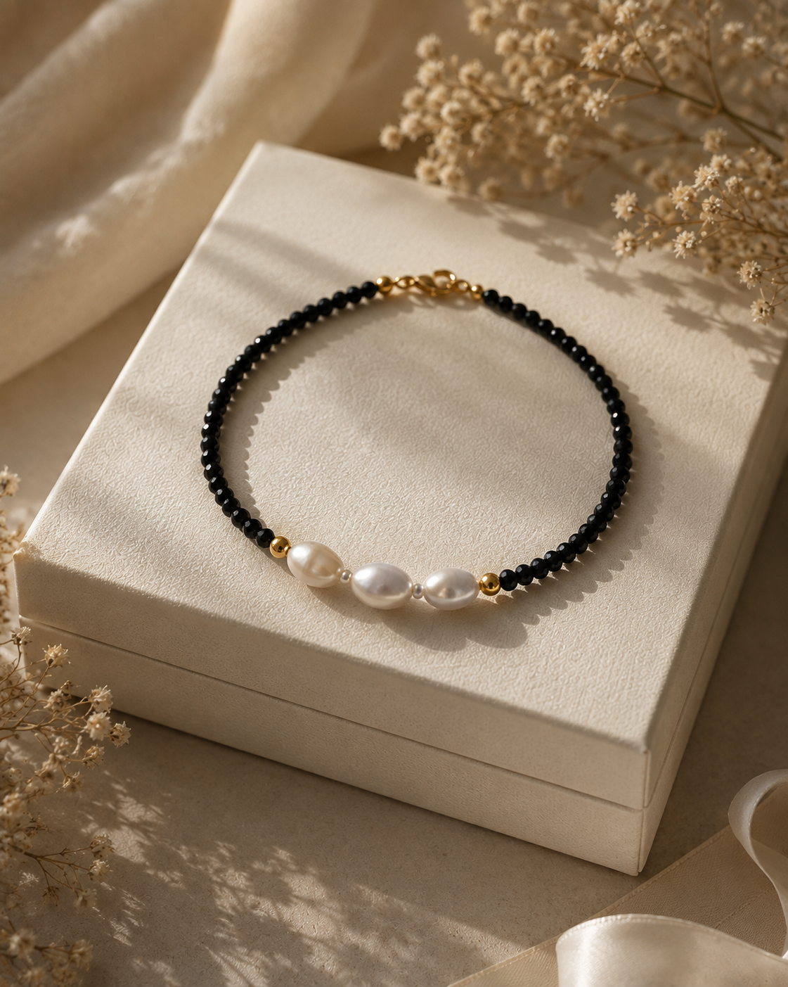 Triple freshwater pearl bracelet with black faceted beads and a gold-tone lobster clasp