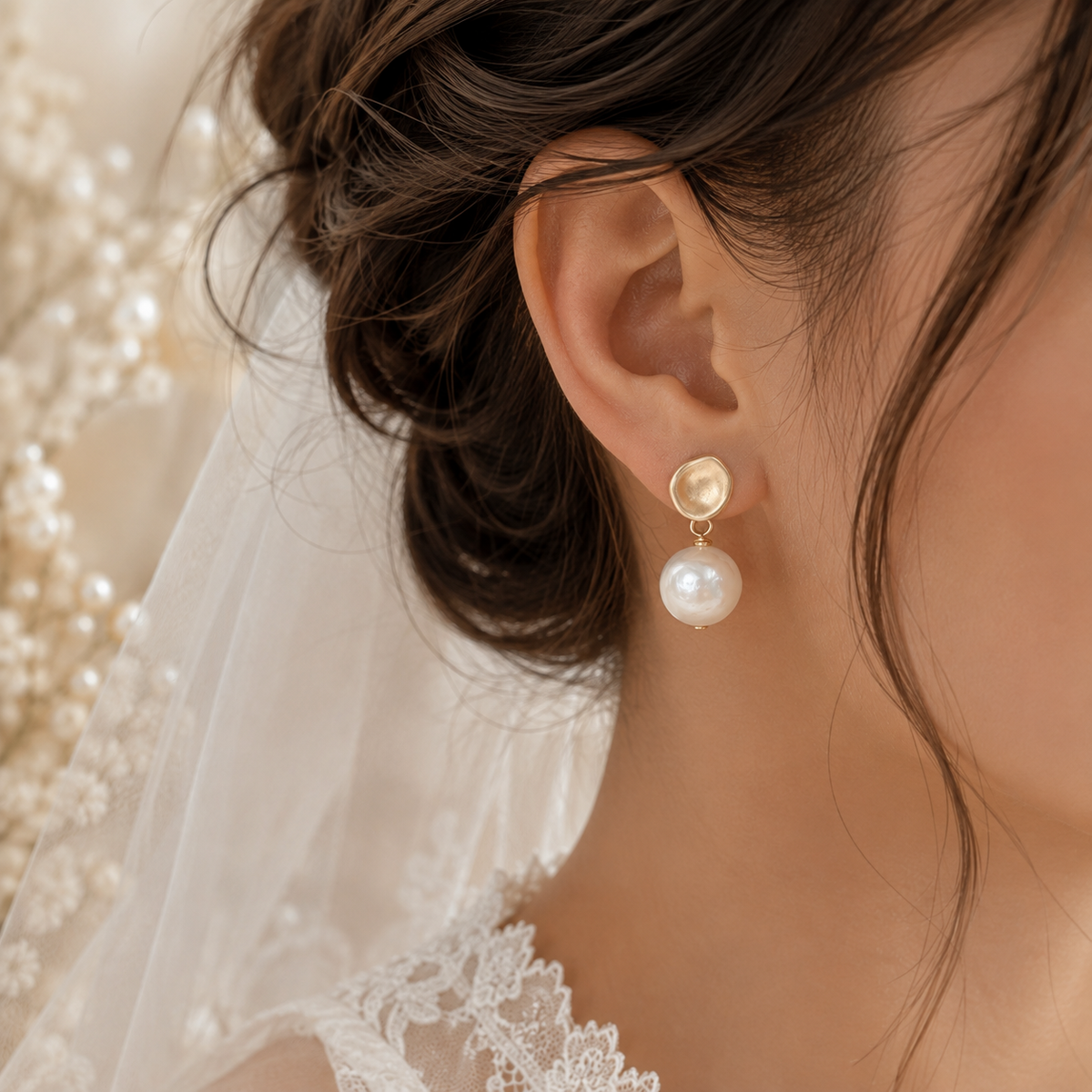 Close-up of a white baroque pearl dangle earring with a matte gold-tone stud