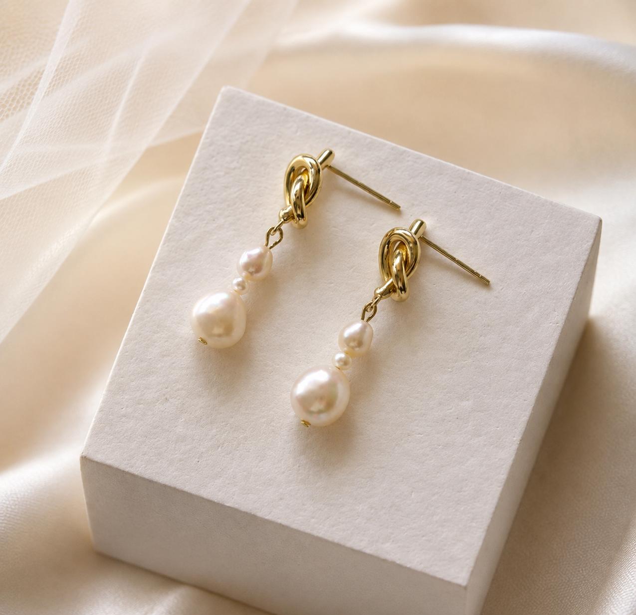 Pair of graduated white freshwater pearl drop earrings with gold-tone knot studs